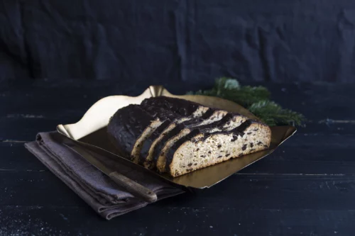 Aufgeschnittener Schokostollen vor Tannenzweig und schwarzem Hintergrund